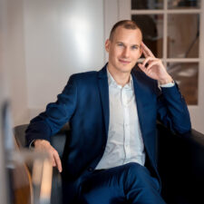 Mann im blauen Anzug sitzt entspannt auf Ledersessel mit Kaffeetasse beim Business Fotoshooting München mit Natalia Schuchardt